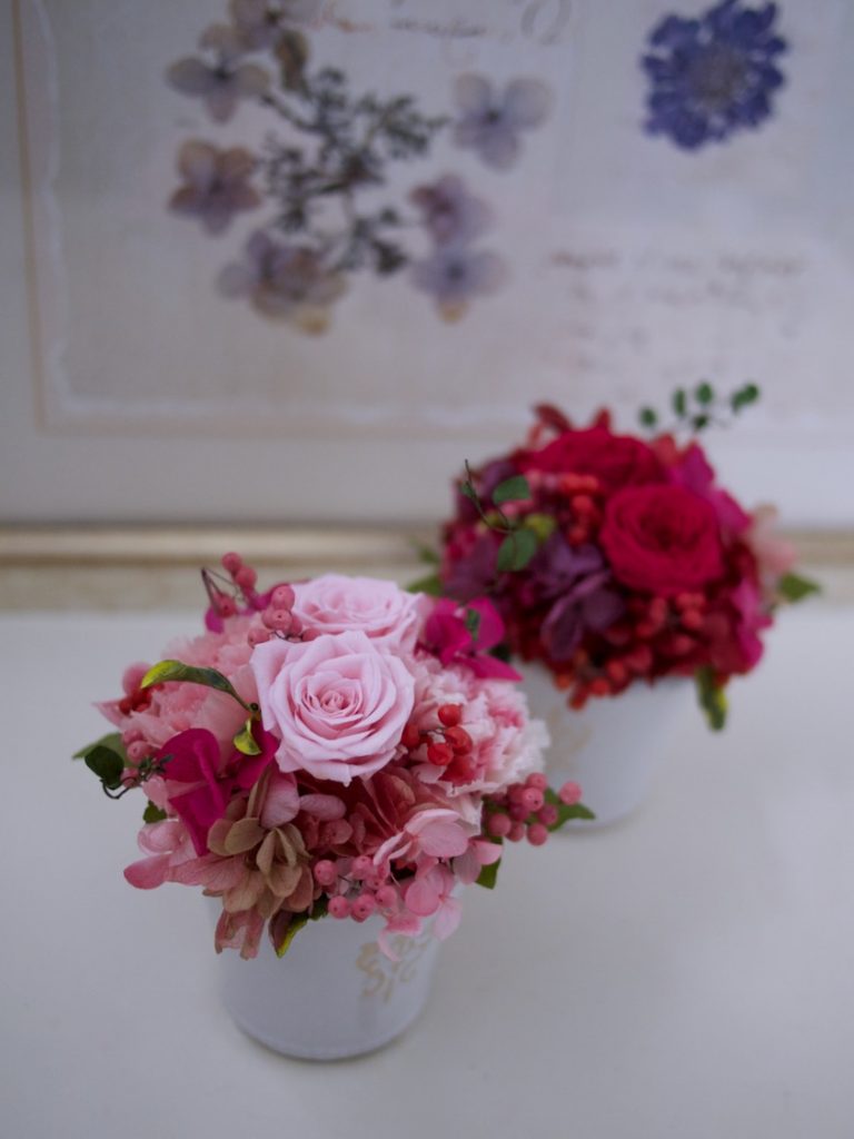 グレーがかった白い花器にピンクと赤のお花をあしらったアレンジ　LUXE